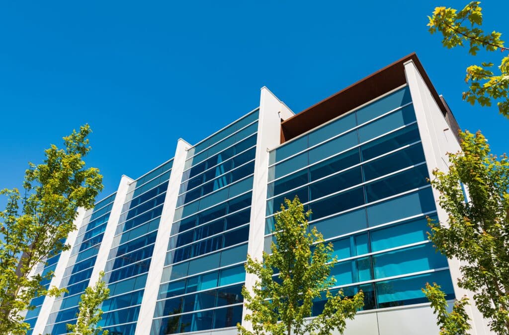 Exterior of a modern office building. Fresh green and building in sunny summer day.